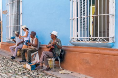 CUBA - 7 Nisan 2016: Renkli bir sokakta kadın turistlerin onlara yaklaştığı sokak şarkıcıları.