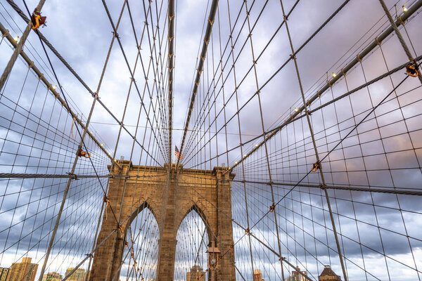 The Brooklyn Bridge at sunset, major pylon and cables against cloudy sky, New York City