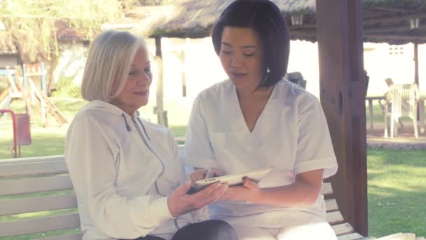 Mid age medical nurse and senior patient outdoors — Stock Video