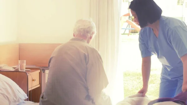 Helping man going out of bed in hospital