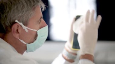 Coronavirüs zamanlarında eldiven takan akıllı telefonları temizleyen doktor. Yavaş çekim