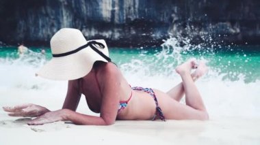 Tatilde plajda uzanmış, hasır şapka takmış güzel bir kadın. Tatil ve seyahat kavramı