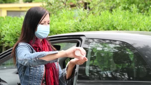 Женщина забирает продукты из машины, дезинфицируя руки и надевая маску от коронавируса — стоковое видео