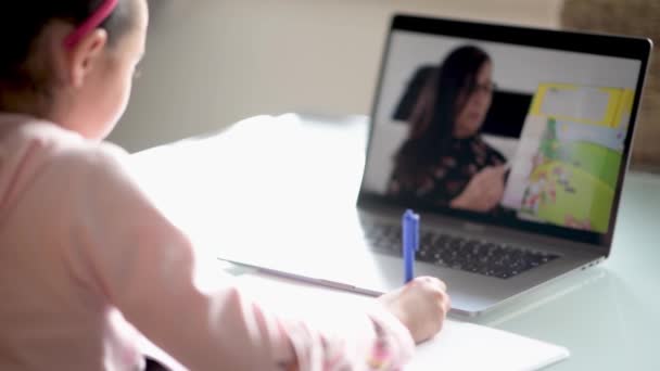 Mladá dívka ze základní školy studuje doma s internetovým chatem s učitelem připravuje na zkoušku. Školní student učení on-line, sledovat webinář dělat poznámky při pohledu na notebook, distanční vzdělávání — Stock video