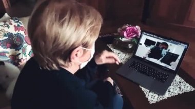Yaşlı kadın Coronavirus zamanlarında doktoruyla video görüşmesinde maske takıyor.