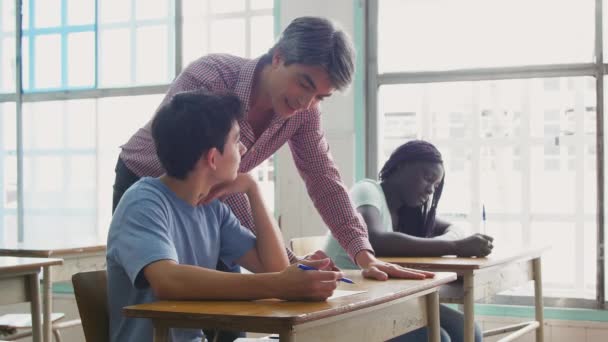 Учитель мужского пола проверяет многонациональный тест в классе — стоковое видео