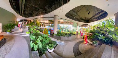 BANGKOK, THAILAND - DECEMBER 16, 2019: Tourists enjoythe Emquartier. It is a famous shopping center. Panoramic view. clipart