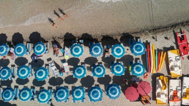 Tropikal bir plajdaki çizgili plaj şemsiyelerinin hava manzarası..