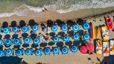Tropikal bir plajdaki çizgili plaj şemsiyelerinin hava manzarası..