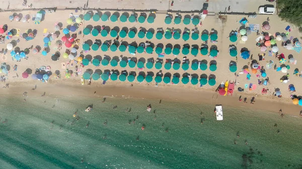 Aerial overhead view of lined beach umbrellas on a tropical beach.