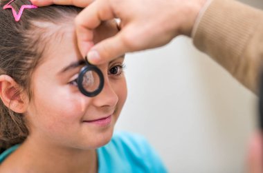 Klinikte göz doktoru tarafından görülen genç kız. Çocuklarda görme ve görme bozukluklarının teşhisi.
