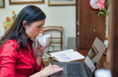 Koronavirüs zamanında çalışmak zekiceydi. Ofisindeki iş kadını bilgisayarla çay yudumluyor..