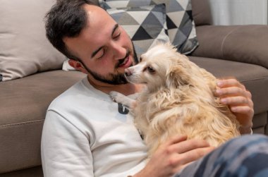 Mutlu adam kanepede oturup köpeğe bakıyor..