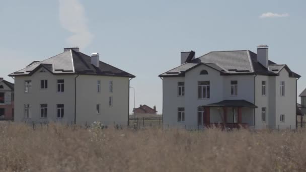 Fazendas. Verão, dia ensolarado. em primeiro plano grama no fundo das casas. Céu azul. linha longitudinalmente da estrada. paisagem rural com casas na grama. Linda aldeia. 02.07.2016 — Vídeo de Stock