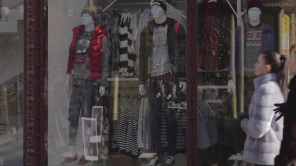 Calles comerciales, una multitud de gente.multitud de personas caminando por la calle comercial. La gente pasa por los escaparates. Otoño, día soleado. La gente camina con la ropa de abrigo. maniquíes vestidos con ropa de pie en un escaparate — Vídeos de Stock