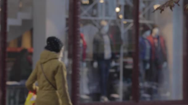 Strade dello shopping, una folla di persone. folla di persone che camminano per la strada dello shopping. La gente passa davanti alle vetrine. Autunno, giornata di sole. La gente cammina con i vestiti caldi. manichini vestiti in stand vestiti in una vetrina — Video Stock