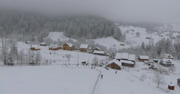 村の冬の山の風景。雪に覆われた木造の上の高さからフライト。冬の村。冬の鳥の目のビューからソウル. — ストック動画