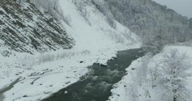 Kış dağlarda. Uçuş kış manzara Dağların üzerinden. Karlı kış dağlarda. Bulutlu kış günü. Dağ manzarası üzerinden bir kuş bakışı.