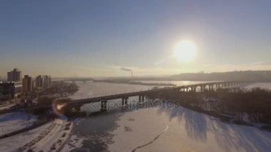 Kiev. Ukrayna. Dinyeper Nehri kış köprüden. Şehri kuşbakışı, gün batımı Lonza ile yayılır. Kiev şehir Dinyeper Nehri üzerinde olduğunu. Kiev batımında Dnieper Nehri üzerinde uçan. Daire binaların çatıları 
