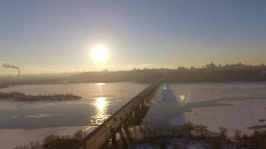 Kiev. Ukrayna. Dinyeper Nehri kış köprüden. Şehri kuşbakışı, gün batımı Lonza ile yayılır. Kiev şehir Dinyeper Nehri üzerinde olduğunu. Kiev batımında Dnieper Nehri üzerinde uçan. Daire binaların çatıları 