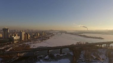 Kiev. Ukrayna. Dinyeper Nehri kış köprüden. Şehri kuşbakışı, gün batımı Lonza ile yayılır. Kiev şehir Dinyeper Nehri üzerinde olduğunu. Kiev batımında Dnieper Nehri üzerinde uçan. Daire binaların çatıları