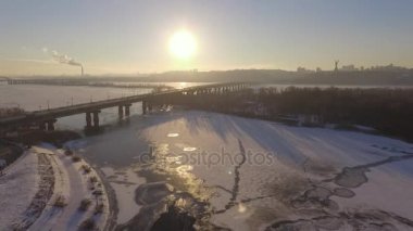 Kiev. Ukrayna. Dinyeper Nehri kış köprüden. Şehri kuşbakışı, gün batımı Lonza ile yayılır. Kiev şehir Dinyeper Nehri üzerinde olduğunu. Kiev batımında Dnieper Nehri üzerinde uçan. Daire binaların çatıları