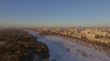 Kiev. Ukrayna. Dinyeper Nehri kış köprüden. Şehri kuşbakışı, gün batımı Lonza ile yayılır. Kiev şehir Dinyeper Nehri üzerinde olduğunu. Kiev batımında Dnieper Nehri üzerinde uçan. Daire binaların çatıları 