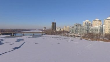 Kiev. Ukrayna. Dinyeper Nehri kış köprüden. Şehri kuşbakışı, gün batımı Lonza ile yayılır. Kiev şehir Dinyeper Nehri üzerinde olduğunu. Kiev batımında Dnieper Nehri üzerinde uçan. Daire binaların çatıları 