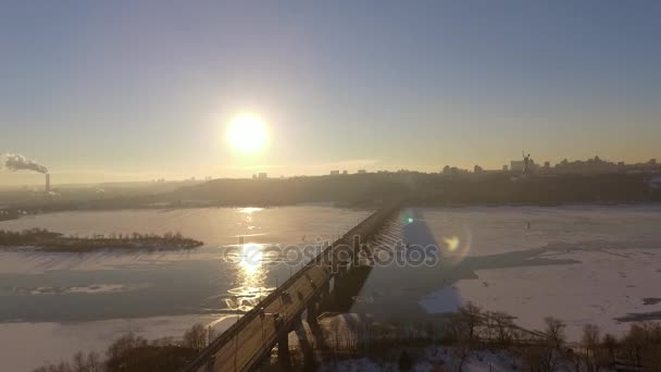 Kijów. Ukraina. Most przez zimę rzeki Dniepr. Rozciągać się na miasto z lotu ptaka widok na zachód słońca Lonza. Kijów jest nad rzeką Dniepr. Latanie w Kijowie nad rzeką Dniepr o zachodzie słońca. Dachy budynków mieszkalnych — Wideo stockowe