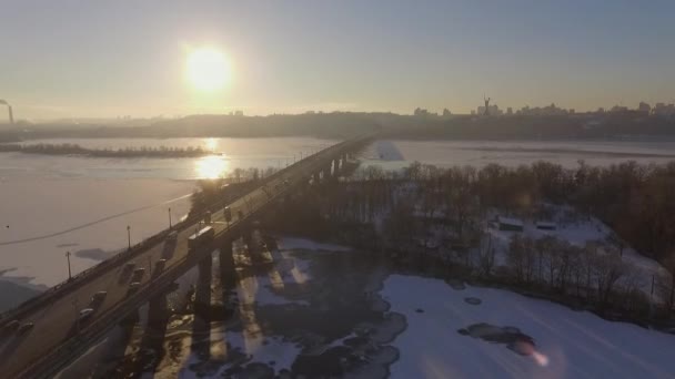 基辅。乌克兰。第聂伯河河冬天大桥。横跨在日落龙沙鸟瞰的城市。基辅市位于第聂伯河。在基辅在日落时在第聂伯河上飞行。公寓楼的屋顶 — 图库视频影像