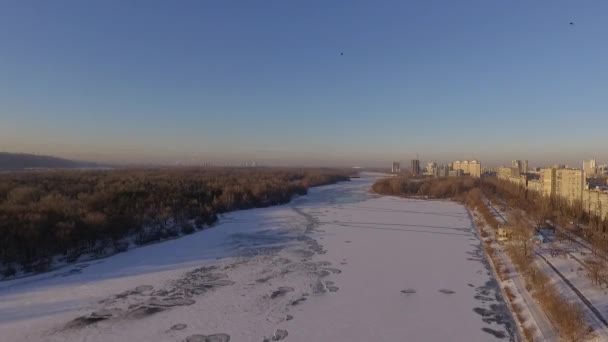 Kiev. Ukrayna. Dinyeper Nehri kış köprüden. Şehri kuşbakışı, gün batımı Lonza ile yayılır. Kiev şehir Dinyeper Nehri üzerinde olduğunu. Kiev batımında Dnieper Nehri üzerinde uçan. Daire binaların çatıları — Stok video