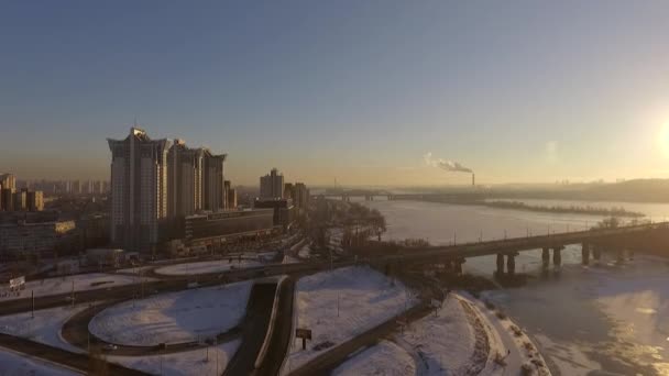 基辅。乌克兰。第聂伯河河冬天大桥。横跨在日落龙沙鸟瞰的城市。基辅市位于第聂伯河。在基辅在日落时在第聂伯河上飞行。公寓楼的屋顶 — 图库视频影像