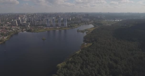 Inquérito aéreo: Kiev-Akademgorodok. a paisagem urbana do ar. Paisagem florestal com vista para o lago e metrópole. um belo lago à beira da cidade. floresta verde com um lago paisagem urbana . — Vídeo de Stock