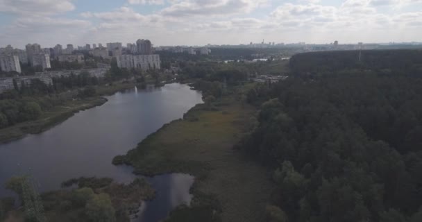 Inquérito aéreo: Kiev-Akademgorodok. a paisagem urbana do ar. Paisagem florestal com vista para o lago e metrópole. um belo lago à beira da cidade. floresta verde com um lago paisagem urbana . — Vídeo de Stock