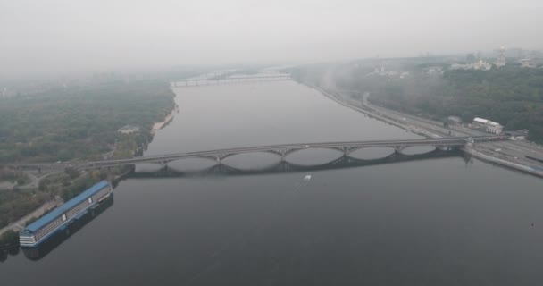 Aéreo. Kiev metro ponte em tempo nublado. Ponte arqueada que passa pelo rio Dnieper a margem esquerda. Névoa sobre o rio e ponte. Bela paisagem urbana com vista para o rio e a ponte . — Vídeo de Stock