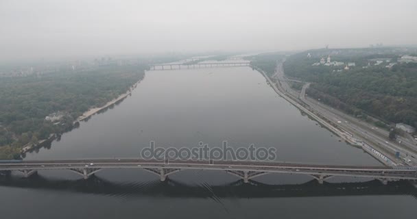 空中。キエフ地下鉄橋曇りの天気。アーチ型の橋は、ドニエプル川左岸を通過します。川と橋を覆う霧。川と橋の景色と美しい街並み. — ストック動画