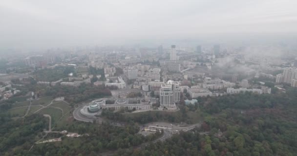 Εναέρια έρευνα. Κίεβο-πάρκο Αιώνιας Δόξας με θέα στην πόλη. Φθινοπωρινό τοπίο, πάρκο και μια μεγάλη μητρόπολη στην ομίχλη. Δέντρα από κίτρινα και κόκκινα άνθη. Πολυώροφα σπίτια στην ομίχλη. — Αρχείο Βίντεο