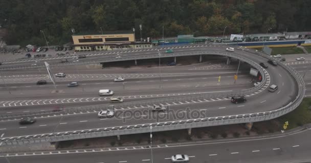 Aerial survey. Kiev-road junction. October 15, 2017. A large number of cars drive along the highway. City landscape, road with cars near the river Dnieper. Period of the year is autumn, cloudy day, fog. — Stock Video