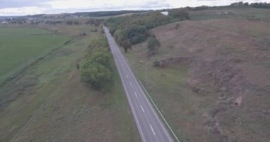 Hava anket. Otoyolu yakınındaki dağ. üstten arabalar manzaralı yol. yeşil ağaçlar yolun yakınlarında. Yaz bulutlu gün. küçük bir nehir yolun kenarında olan bir alana. Karayolu boyunca araçları çalıştırmak.