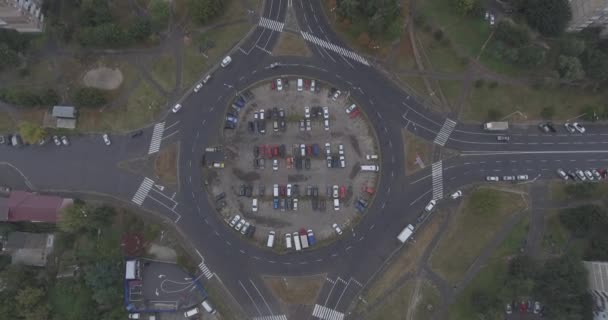 Légi felmérés. körkörös főút csomópontja. A körgyűrű közepén van egy parkoló. autók állva egy ágy. nyári borús napon. — Stock videók