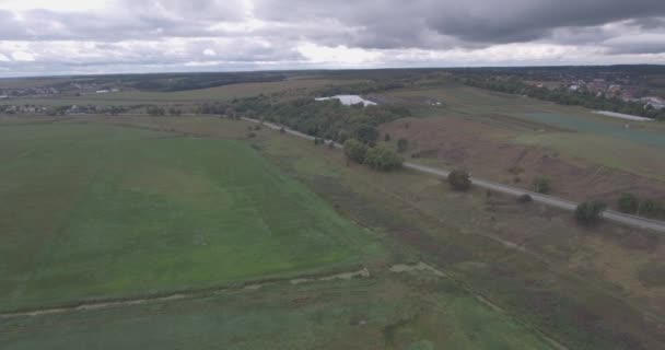 Indagine aerea. autostrada vicino alla montagna. strada con auto vista dall'alto. alberi verdi vicino alla strada. giornata estiva nuvolosa. un campo con un piccolo fiume vicino alla strada. auto corrono lungo l'autostrada . — Video Stock