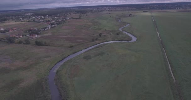 Inspección aérea. un pequeño río pasa a través de un campo verde. Un hermoso campo con vista al río desde la vista de un pájaro. día de verano, las sombras de las nubes yacen en el campo . — Vídeos de Stock