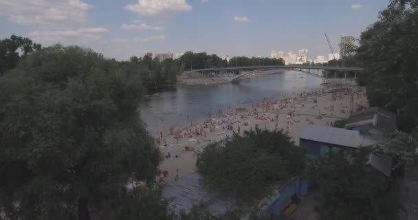 Antena z plaży. słoneczny letni dzień, ludzie są opalając się na żółtym piszczenie na brzegu Dniepru rzeki Kijowa. dzień wolny, wakacje na plaży. duża liczba turystów pływać. — Wideo stockowe