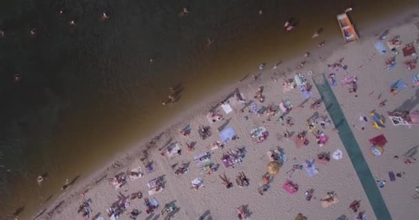 Antena z plaży. słoneczny letni dzień, ludzie są opalając się na żółtym piszczenie na brzegu Dniepru rzeki Kijowa. dzień wolny, wakacje na plaży. duża liczba turystów pływać. — Wideo stockowe