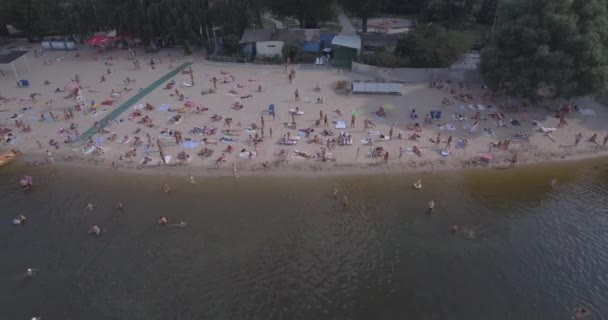 Aérea de la playa. día soleado de verano, la gente está tomando el sol en un chirrido amarillo en la orilla de la ciudad del río Dniéper de Kiev. día libre, vacaciones en la playa. un gran número de turistas nadan . — Vídeos de Stock