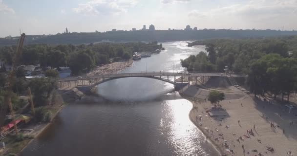 Antena z plaży. słoneczny letni dzień, ludzie są opalając się na żółtym piszczenie na brzegu Dniepru rzeki Kijowa. dzień wolny, wakacje na plaży. duża liczba turystów pływać. — Wideo stockowe