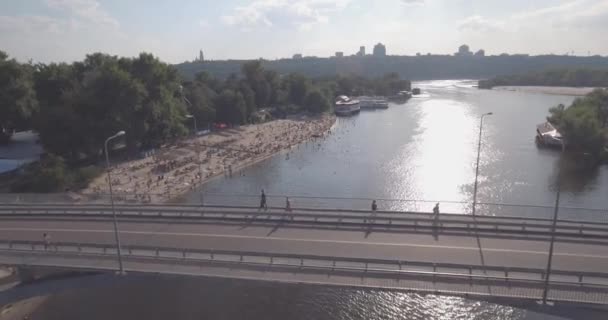 Antenne de la plage. journée ensoleillée d'été, les gens prennent un bain de soleil sur un grincement jaune sur la rive de la ville de la rivière Dniepr de Kiev. jour de congé, vacances sur la plage. un grand nombre de touristes nagent . — Video