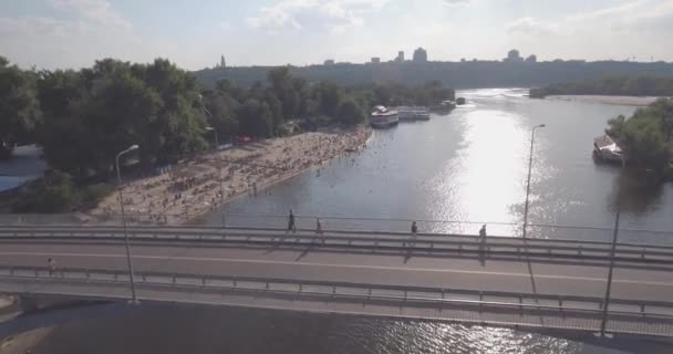 Antena z plaży. słoneczny letni dzień, ludzie są opalając się na żółtym piszczenie na brzegu Dniepru rzeki Kijowa. dzień wolny, wakacje na plaży. duża liczba turystów pływać. — Wideo stockowe