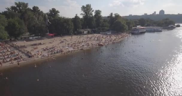 Воздушное пространство пляжа. летний солнечный день, люди загорают на желтом скрипе на берегу Днепра. выходной, отпуск на пляже. большое количество туристов плавает . — стоковое видео