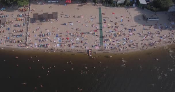 ビーチのアンテナ。夏の晴れた日、キエフのドニエプル川都市の土手に黄色のきしむ音で人々 の日光浴が。ビーチでの休暇をオフ日。多数のツーリストが泳ぐ. — ストック動画